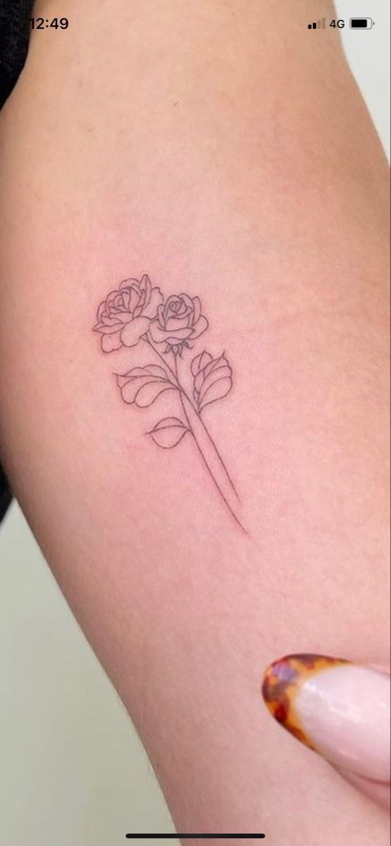 a woman's thigh with a small flower tattoo on her left side ribcage