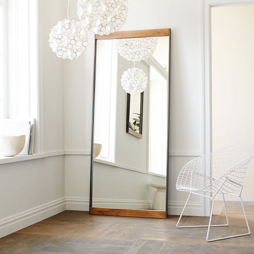 a room with a large mirror, chair and table in the corner next to it