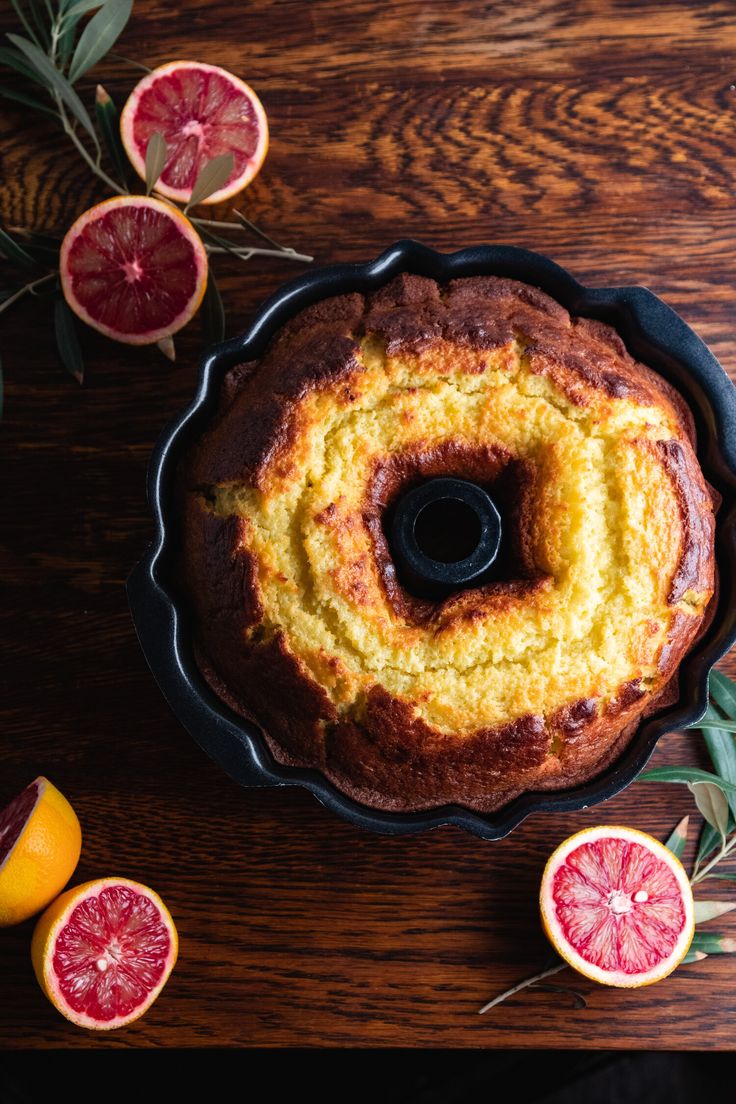 a bundt cake with oranges and grapefruit on the side next to it