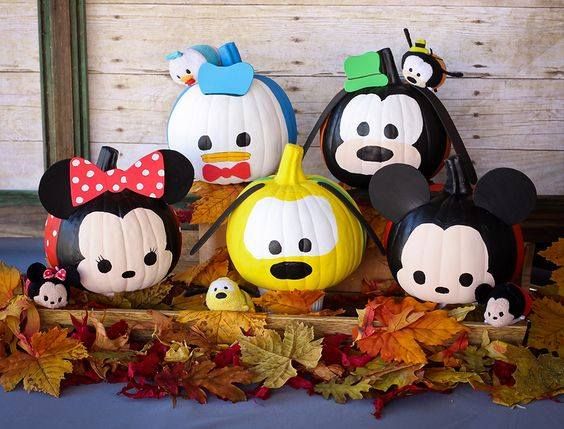 mickey mouse pumpkins and other decorations are on display in front of a wooden wall