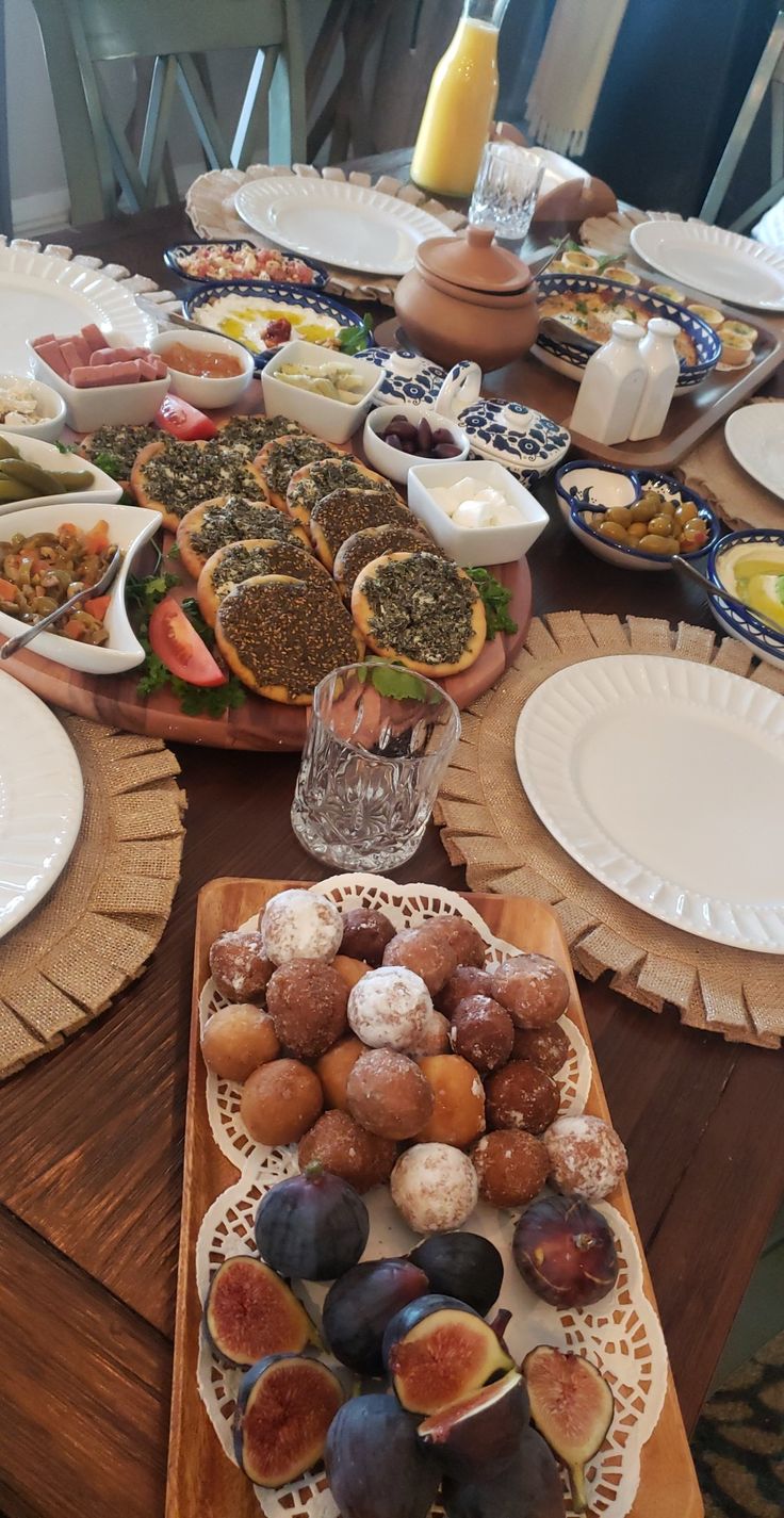 a wooden table topped with lots of plates and bowls filled with different types of food