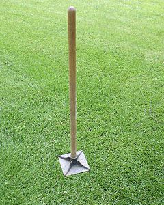 a wooden pole with a metal base in the grass