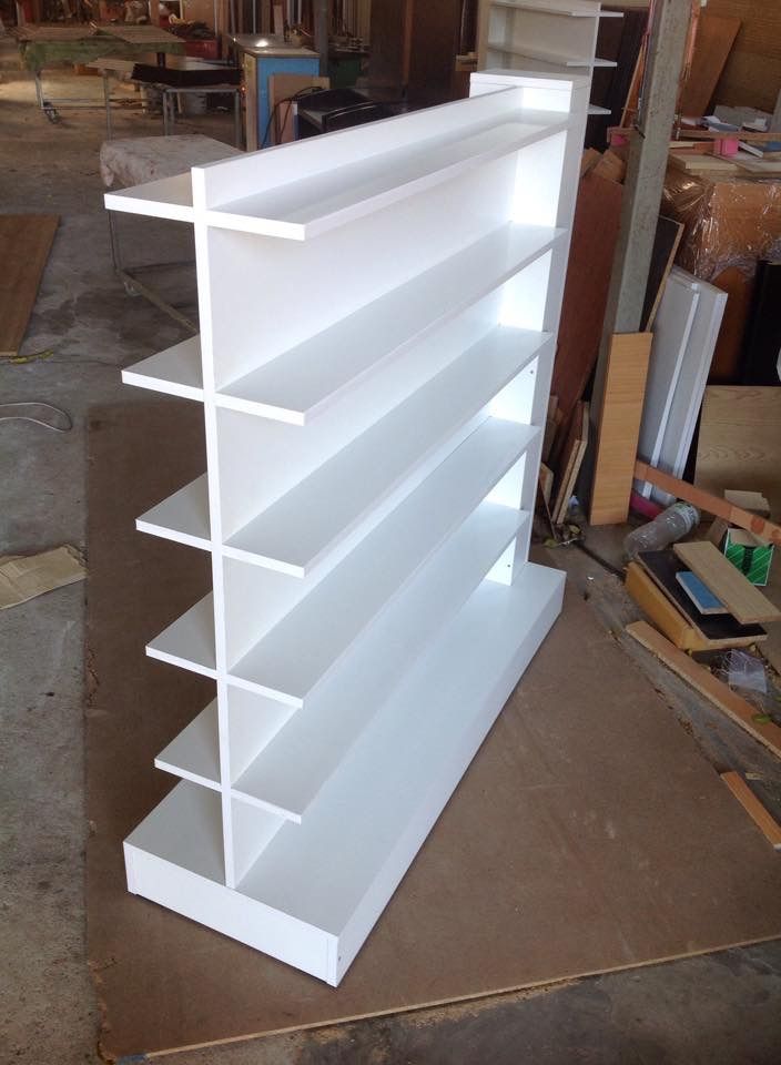 a white book shelf sitting on top of a floor next to a pile of wood