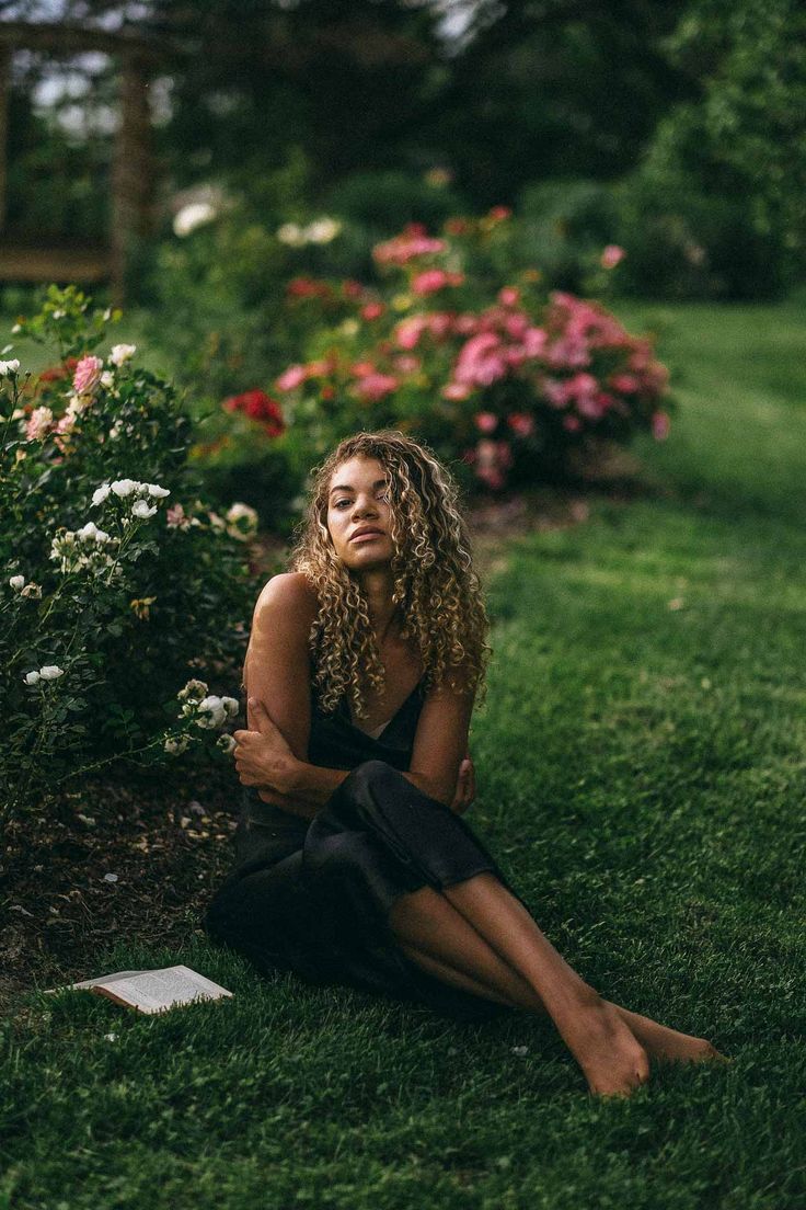 a woman sitting in the grass with her eyes closed and hands folded on her knees