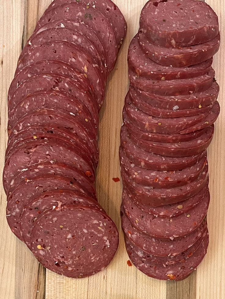 several slices of salami sitting on top of a wooden cutting board