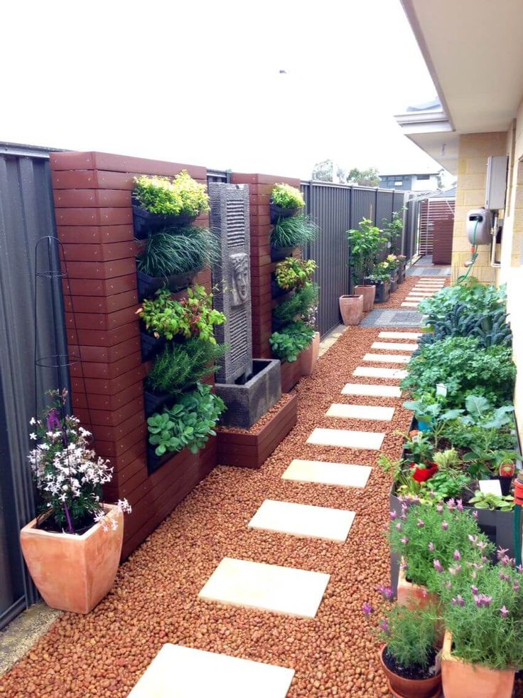 an outdoor garden with lots of plants growing on the walls and walkways between two buildings