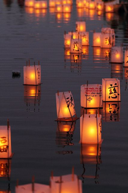 paper lanterns floating in the water at night