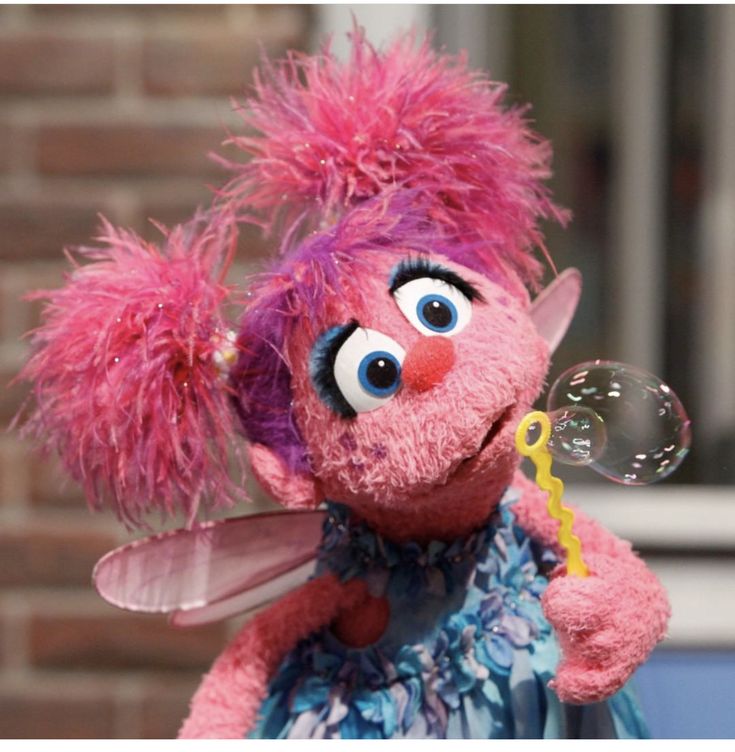 a pink stuffed animal with big eyes blowing bubbles