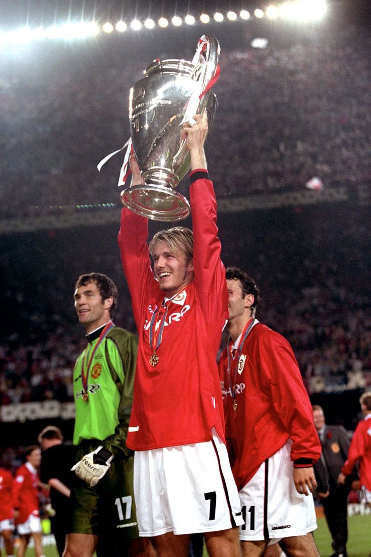 a man holding up a trophy in front of his face while standing on top of a soccer field