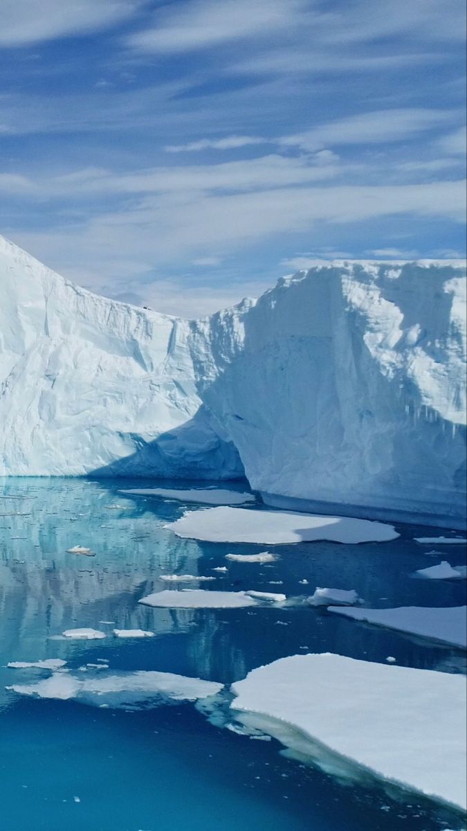 an iceberg in the water with snow on it's sides and blue sky