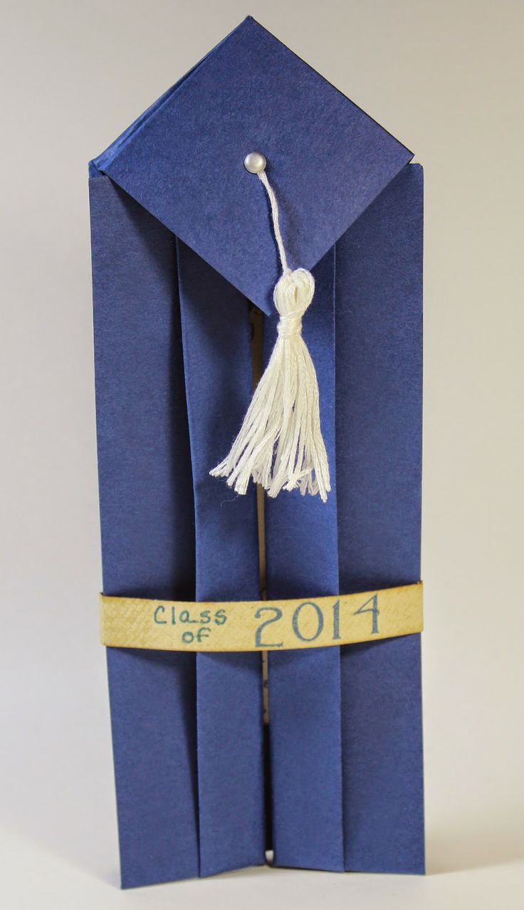 an origami graduation cap and tassel on top of a blue card board