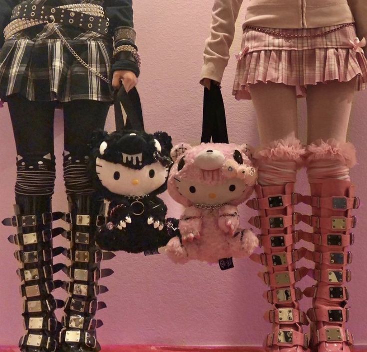 two hello kitty dolls are standing next to each other in front of a pink wall