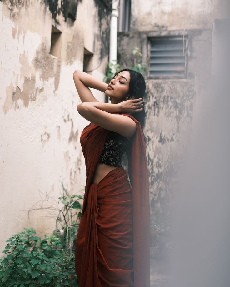 a woman in an orange sari is leaning against a wall