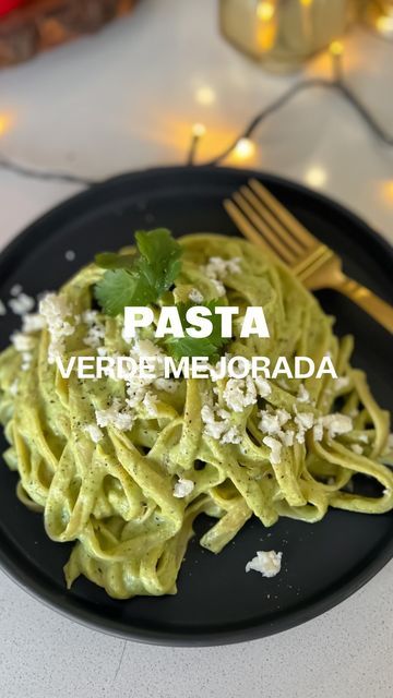 a black plate topped with pasta covered in pesto