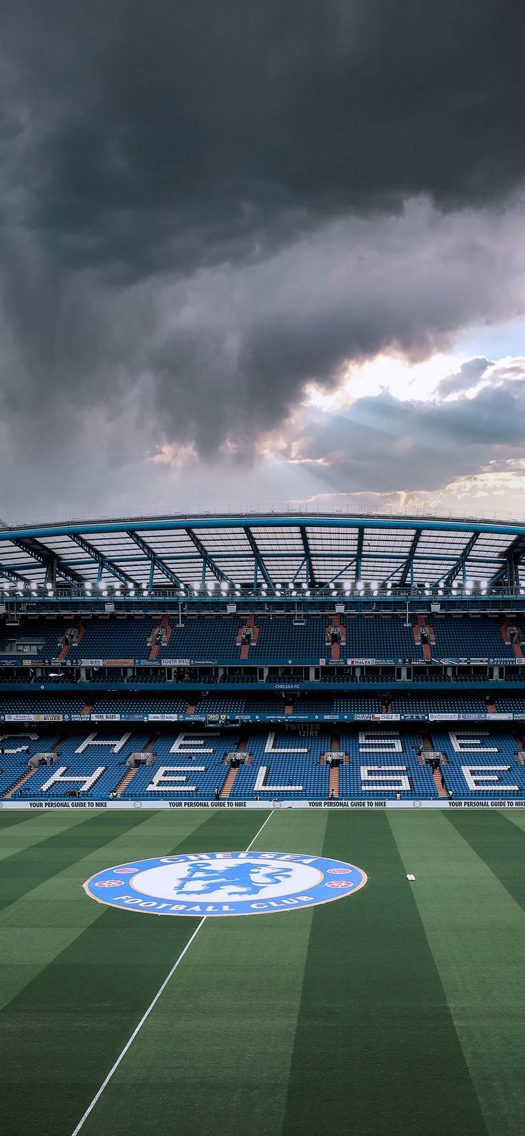 an empty soccer stadium with storm clouds in the background