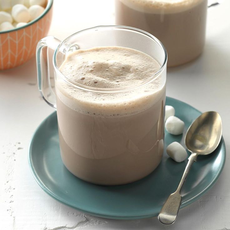 two mugs filled with liquid sitting on top of a blue plate next to some spoons