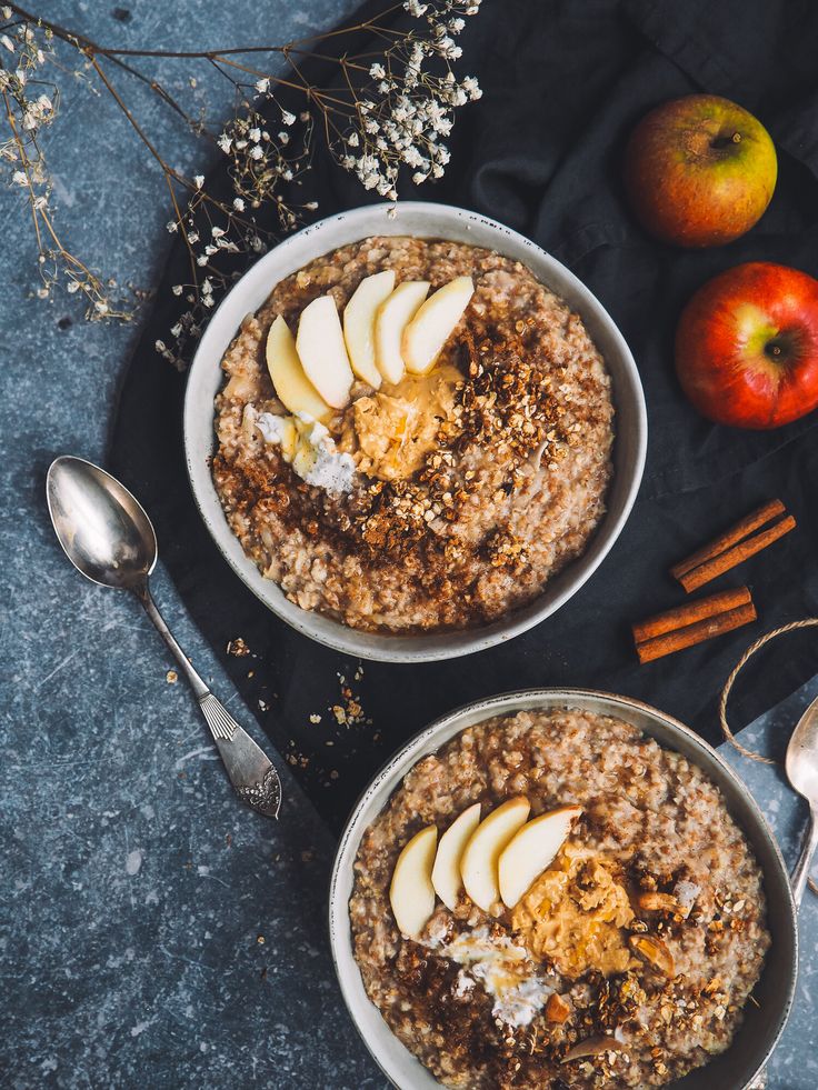 two bowls filled with oatmeal topped with apples