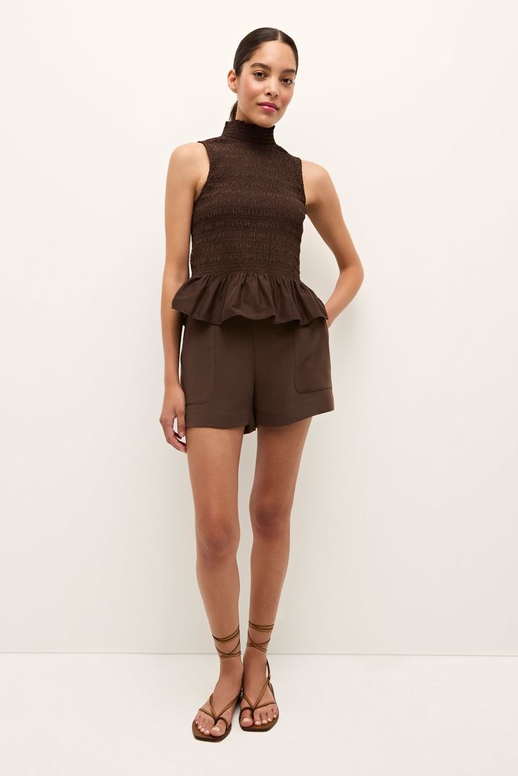 Peplums are back, and we couldn’t be more excited to welcome the playful flattering shape back into the wardrobe rotation. With a fitted smocked bodice, mock funnel neck, a signature peplum hem, the Odie top comes in our rich Walnut hue, the perfect colorway to make the jump to fall. -Elastic smocked fitted bodice-Center back invisible zipper-100% polyester-Partially lined-True to size-Care instructions: hand wash with gentle detergent and hang dry or dry clean Fitted Smocked Top For Daywear In Fall, Fitted Smocked Top For Fall Daywear, Fitted Tops With Gathered Waist For Daywear, Fall Fitted Smocked Top With Ruffles, Fitted Smocked Top With Ruffles For Fall, Fitted Smocked Top For Workwear In Fall, Chic Smock Tops, Fitted Sleeveless Top With Gathered Waist, Elegant Fitted Top With Gathered Waist