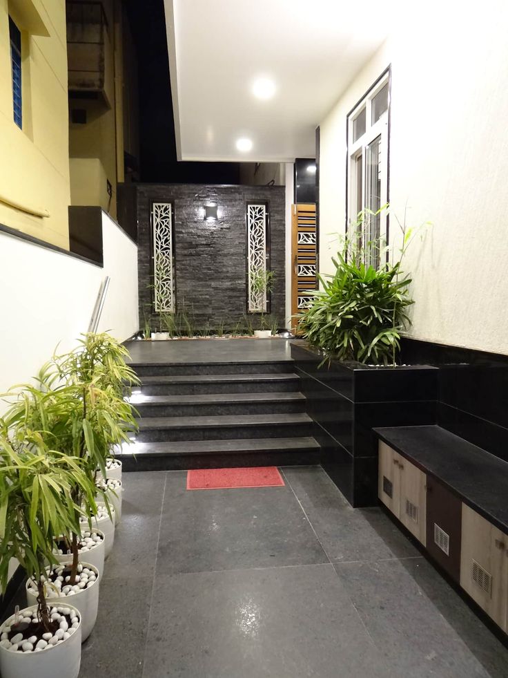 a long hallway with black and white steps leading to potted plants on either side