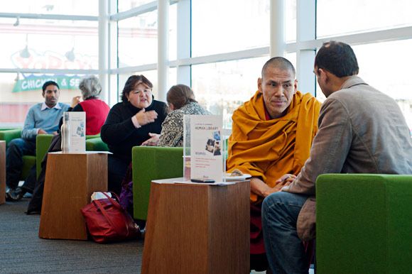 several people sitting in chairs and talking to each other at the same time, one man is wearing a yellow robe