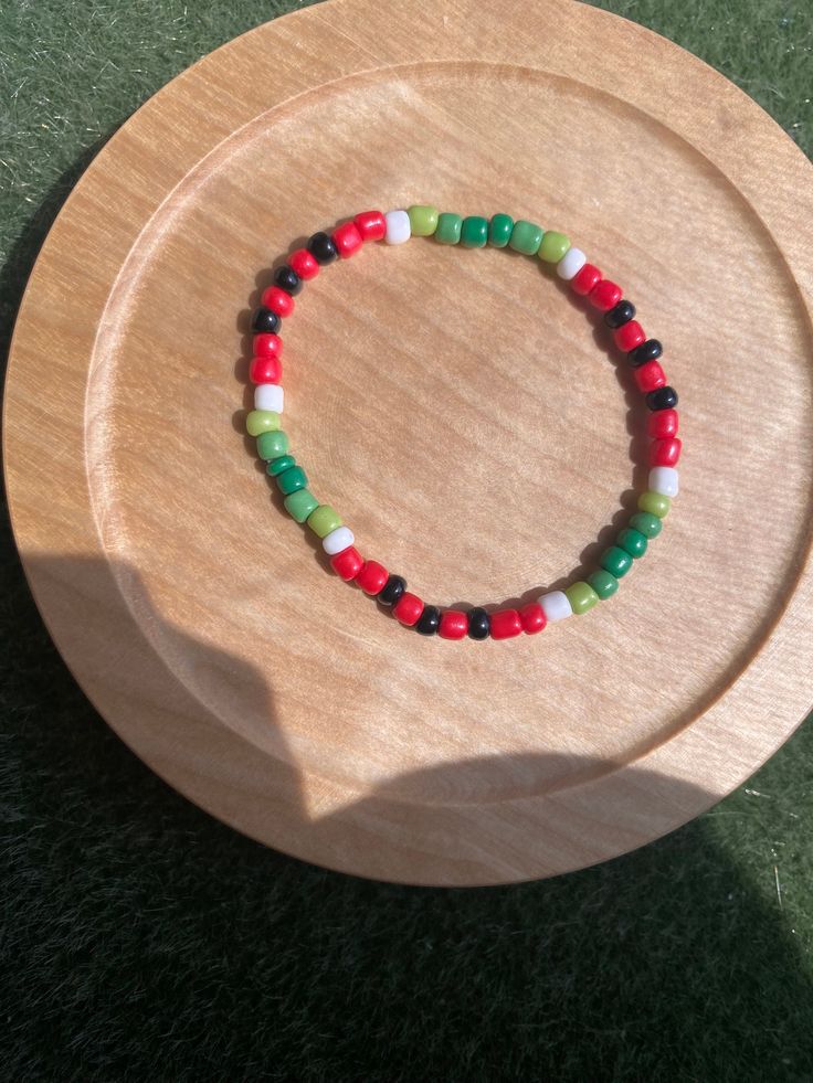 a wooden plate topped with a bracelet on top of it's side and green grass in the background