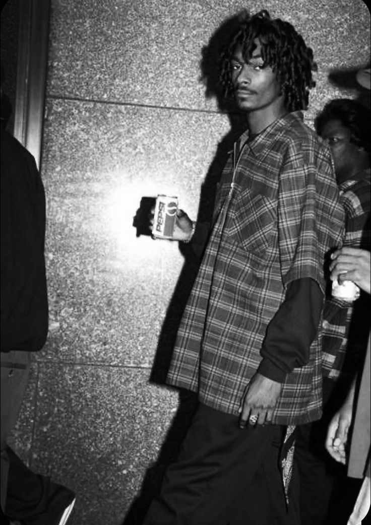 a man with curly hair is walking down the street while holding a coffee cup in his hand