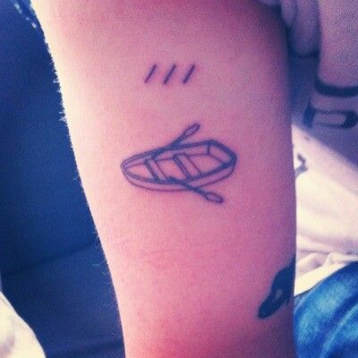 a person with a tattoo on their arm has a boat and oars in the water