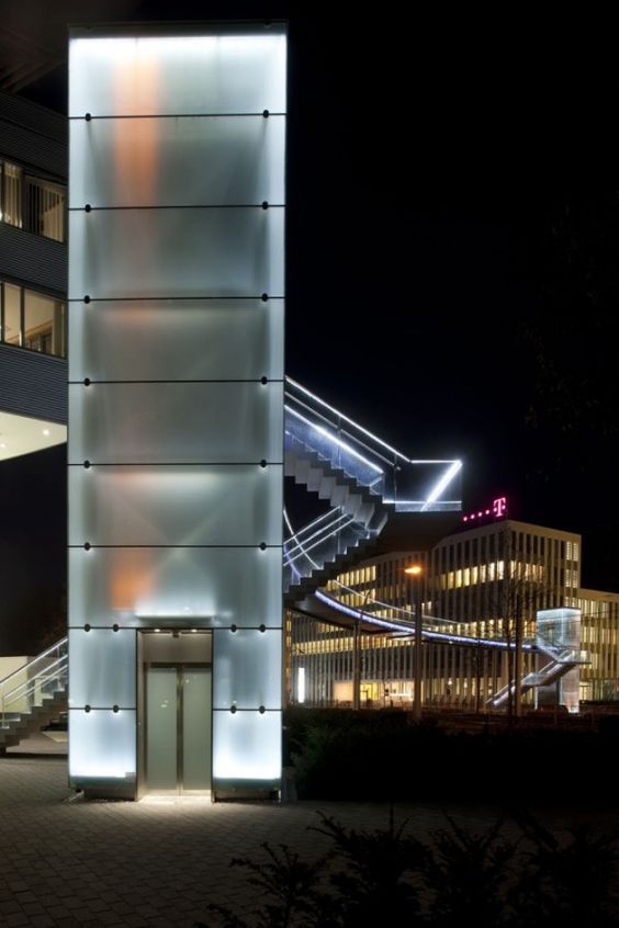 a tall building with lights on it's sides and stairs leading up to the top