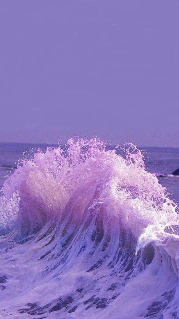 a person riding a surfboard on top of a wave in the ocean with purple hues