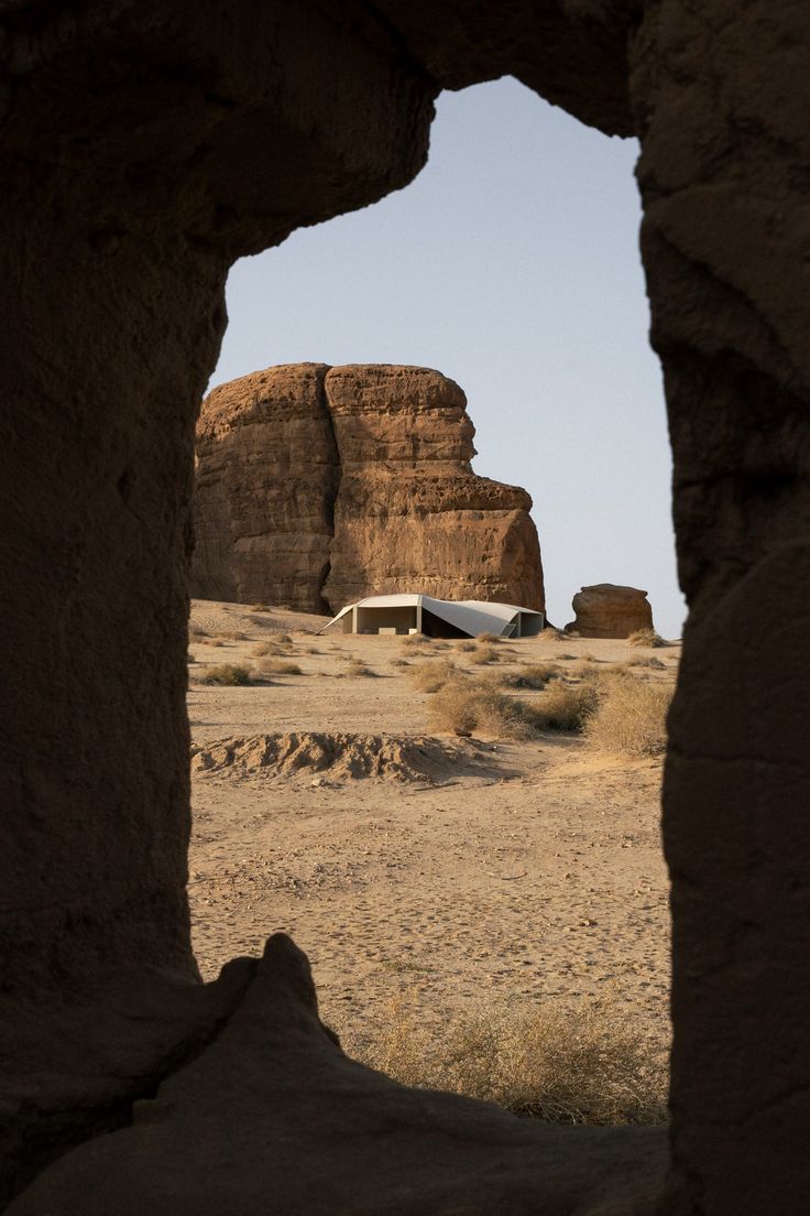 an open window in the side of a rock formation with a small house on it