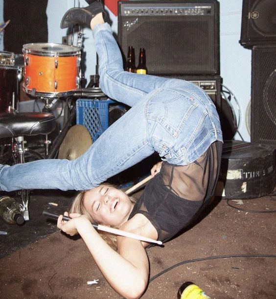 a woman laying on the ground with her legs up in the air while playing drums