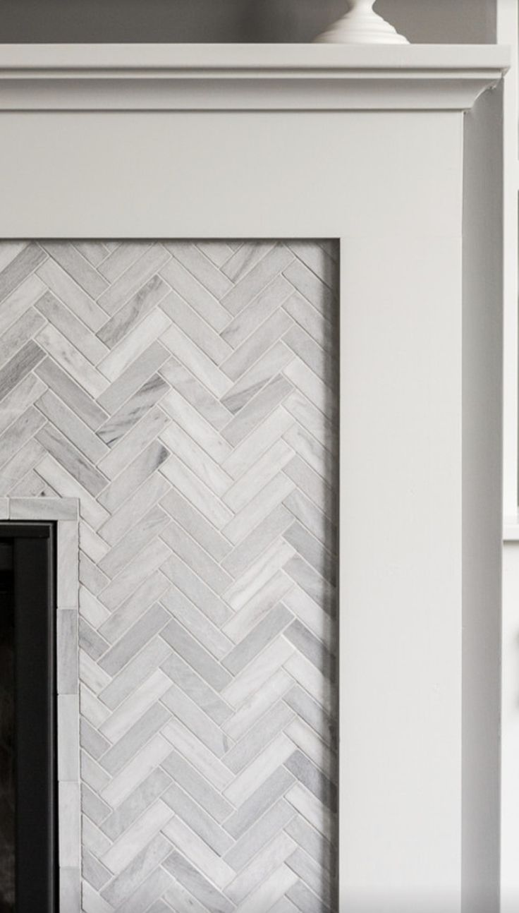 a fireplace with white and grey herringbone tile