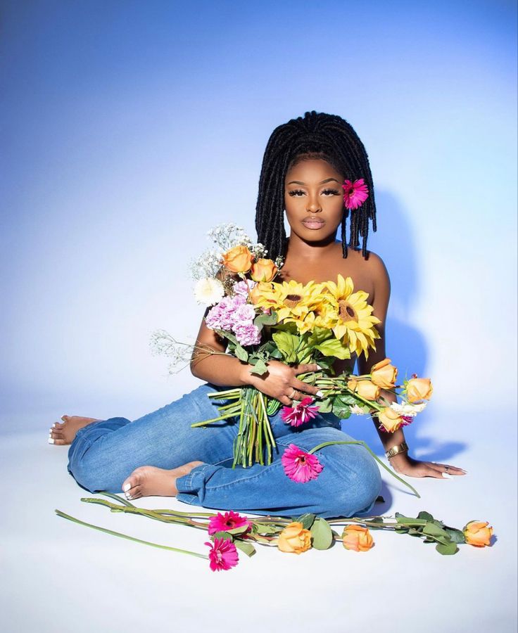 a woman sitting on the ground with flowers in her hands