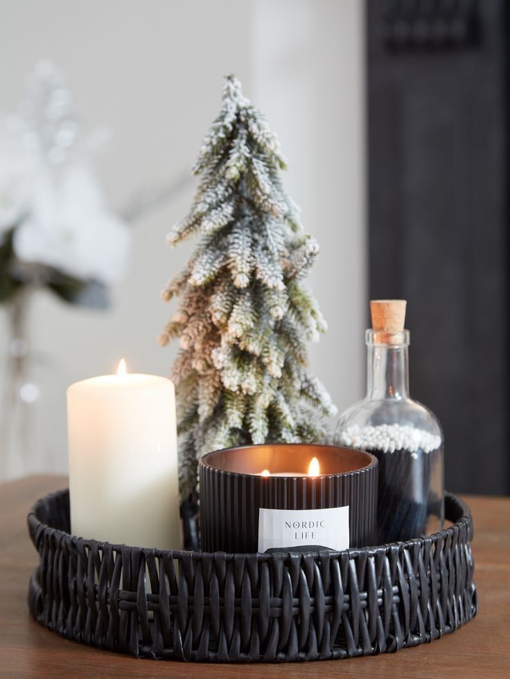 a candle and some bottles sitting on a table next to a christmas tree in a basket