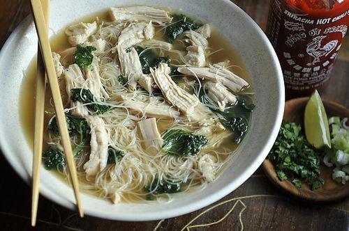 a bowl of chicken noodle soup with chopsticks next to it on a table