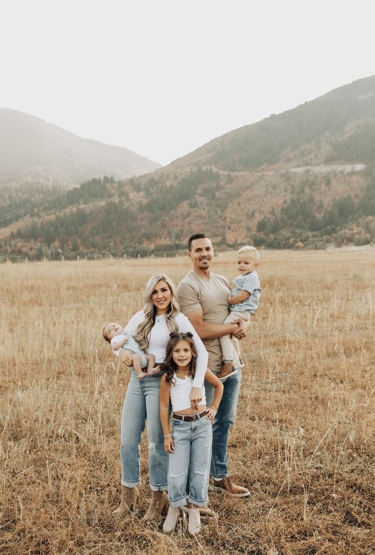 a family poses for a photo in a field with mountains in the backgroud