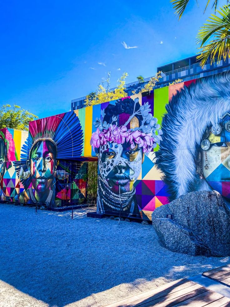 colorfully painted murals on the side of a building with palm trees in the foreground