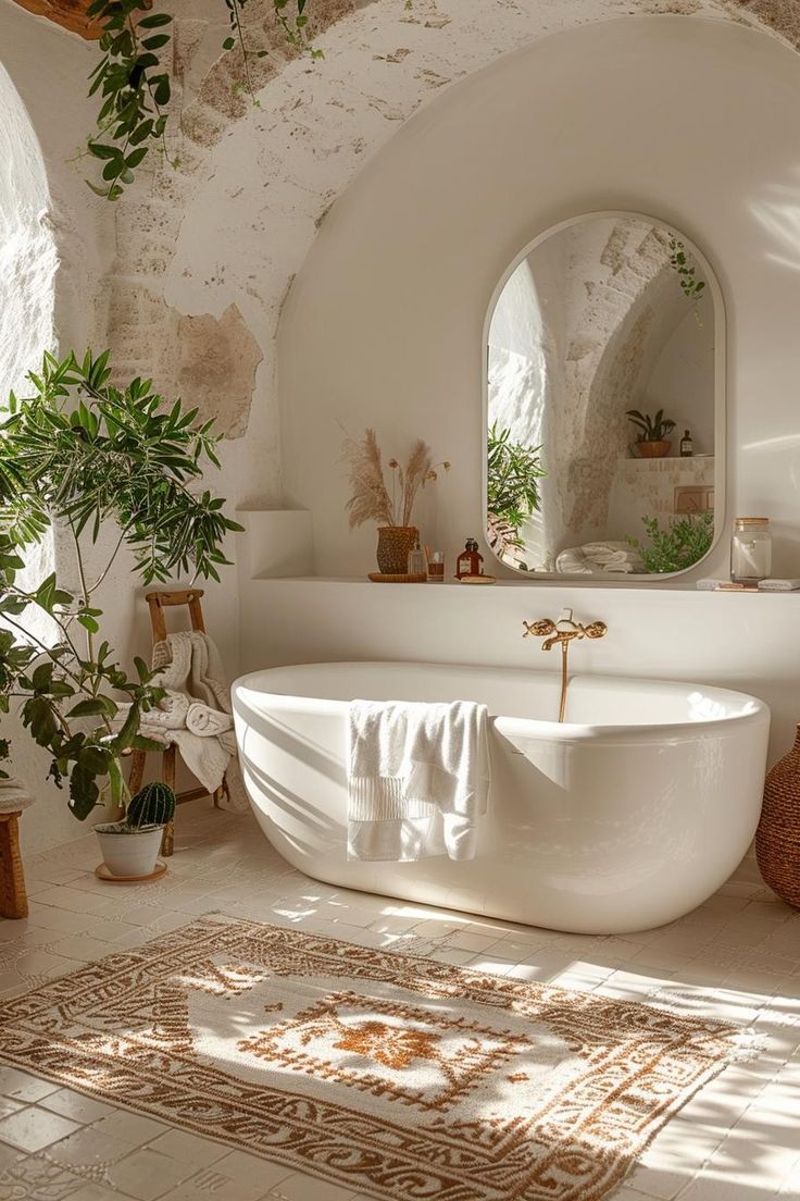 a white bath tub sitting under a window next to a potted plant and mirror