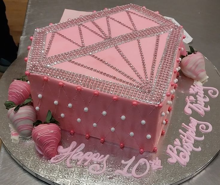 a birthday cake with pink frosting and decorations on it, sitting on a silver platter