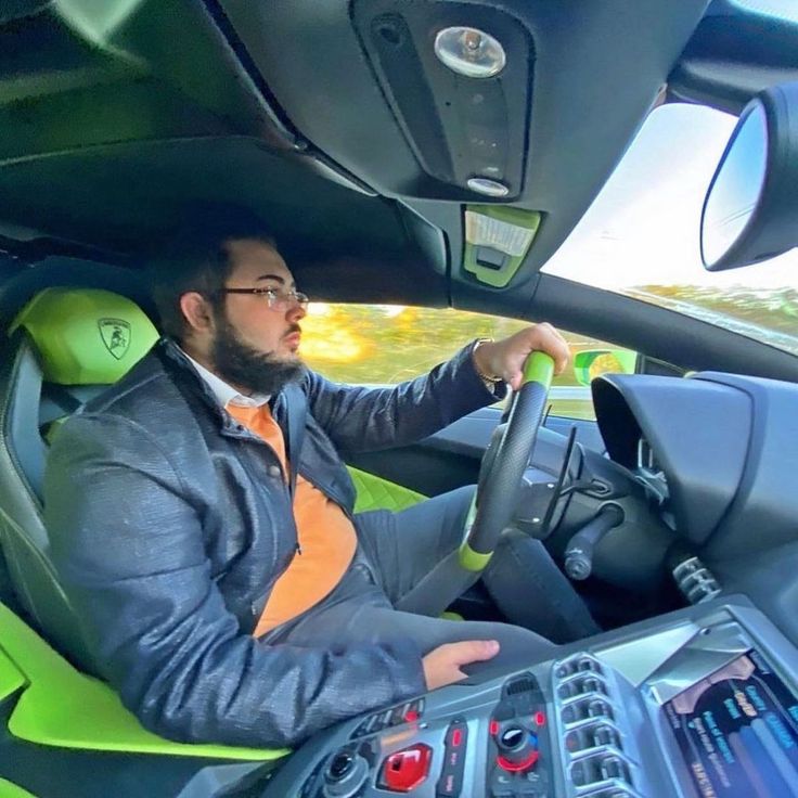 a man sitting in the driver's seat of a car holding a steering wheel