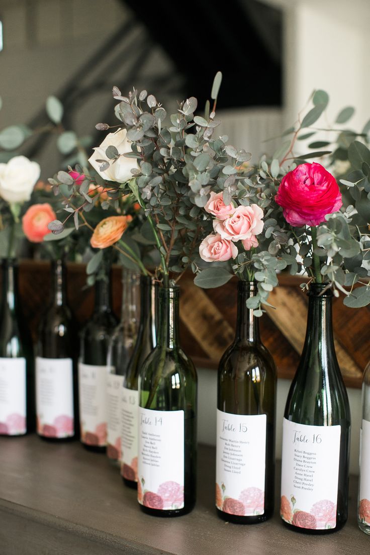 several wine bottles with flowers in them are lined up on a table next to each other