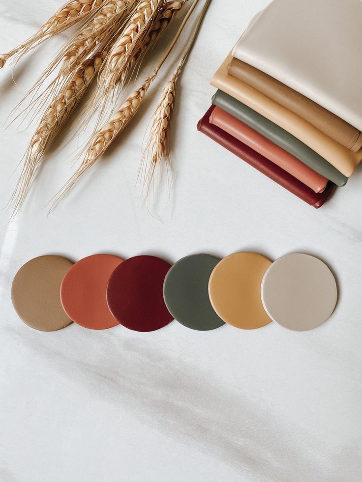 various colors of paper on a table with wheat stalks and other items in the background