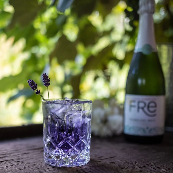 a bottle of wine and a glass with ice cubes on a table next to it