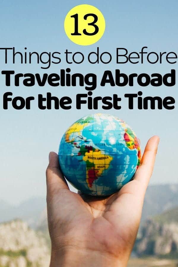 a hand holding a small globe with the words 13 things to do before traveling around the first time