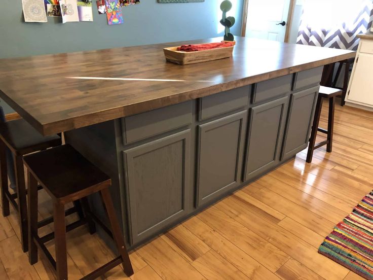 a kitchen island with two stools next to it on top of a hard wood floor