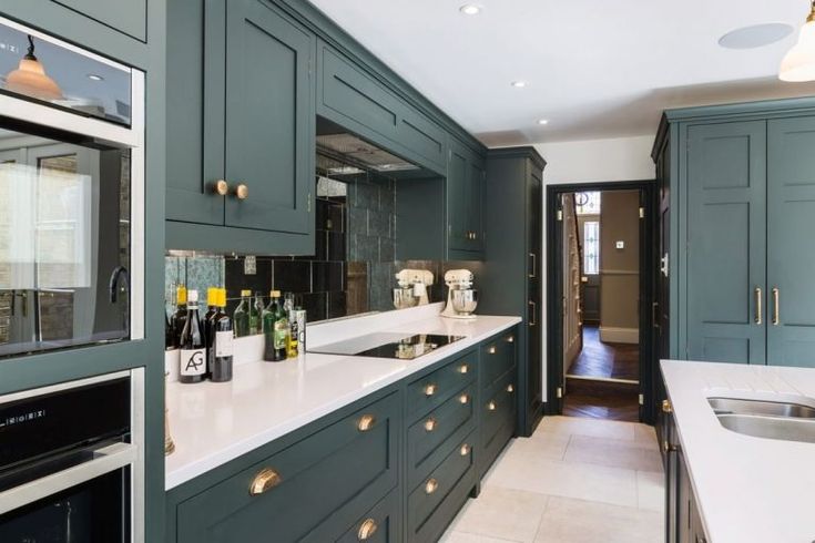 a kitchen filled with lots of green cabinets and counter top space next to a sink