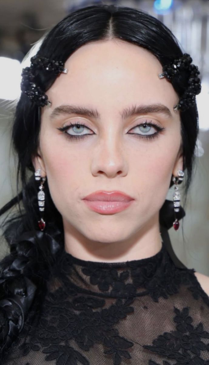 a woman with dark hair and blue eyes wearing black lace dress, earrings and headpieces