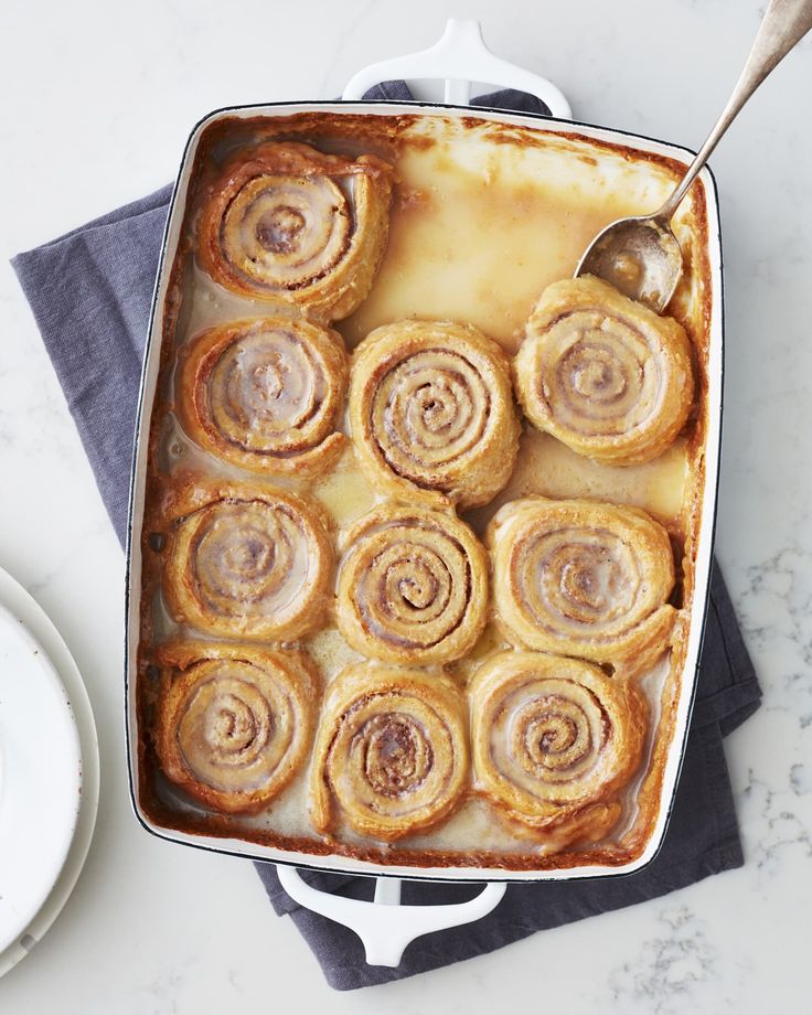 a casserole dish filled with cinnamon rolls on top of a marble countertop