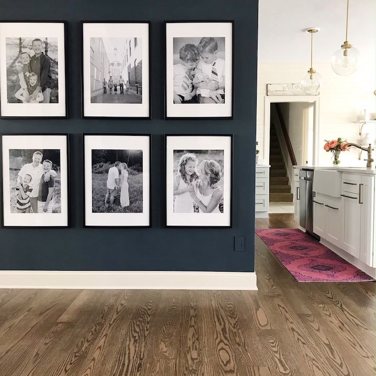 black and white photographs hanging on the wall in a room with wood flooring, blue walls