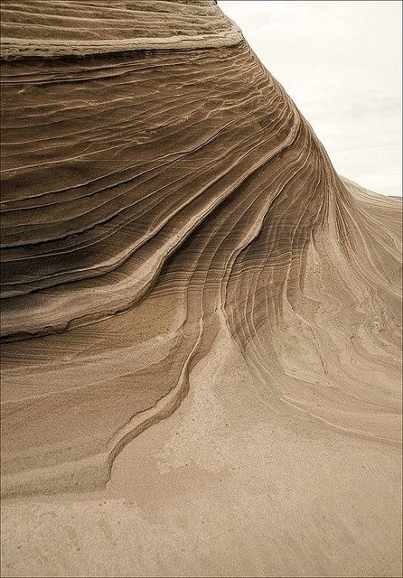 a person riding a surfboard on top of a wave covered sand dune in the ocean